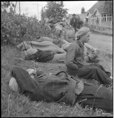 Matkan rasituksesta väsyneet evakot lepäävät ja nukkuvat tienpuolessa. Ilmee 22.6.1944. SA-Kuva.